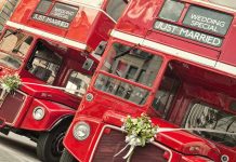 Two red double-decker buses decorated for a wedding with Just Married signs