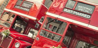 Two red double-decker buses decorated for a wedding with Just Married signs