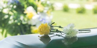 Yellow and white flowers on a green casket
