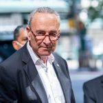 Schumer’s Epstein Remark: Political Bombshell Drops Man in suit and red glasses standing outside