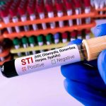 Gloved hand holding STI test tube labeled Negative