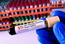 Gloved hand holding STI test tube labeled Negative