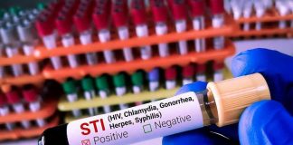 Gloved hand holding STI test tube labeled Negative