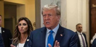 Man speaking with hands raised woman and security behind