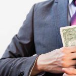 4.5% APY: Why Millionaires Are Banking Big Person in suit putting dollars in jacket pocke