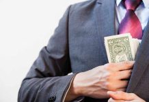 Person in suit putting dollars in jacket pocke