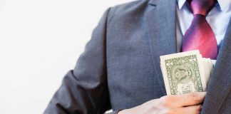 Person in suit putting dollars in jacket pocke