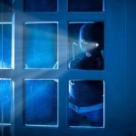 Masked figure peering through glass door at night