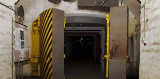 Entrance to an underground bunker with large heavy doors and a sign