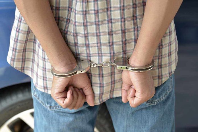 shutterstock_215366989.jpg A person in handcuffs viewed from behind wearing a plaid shirt and denim jeans
