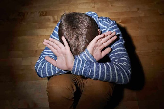 shutterstock_237679426.jpg A child sitting on the floor with their hands covering their face expressing distress