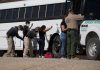 Border patrol officers investigating people near a bus.