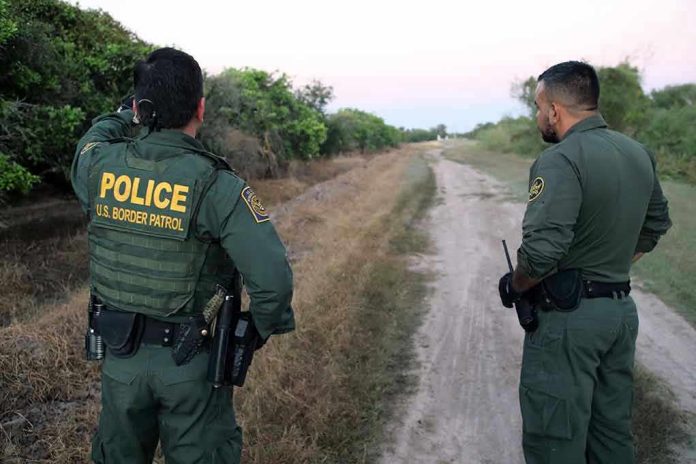 2079342073 Two U.S. Border Patrol officers observing a dirt path.