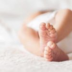 Man Arrested Attempting Baby Purchase Close-up of baby feet lying on blanket.