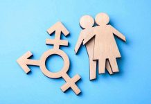 Wooden transgender symbol and couple figures on blue background.