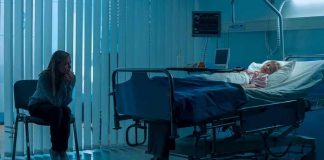 Woman sitting beside hospital bed at night.