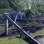 Industrial coal processing plant with conveyor belts and smokestack.