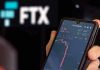 Hand holding phone with FTX trading app.
