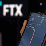 Hand holding phone with FTX trading app.