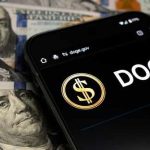 Crypto Student TORTURED – Wallets Drained Alive Smartphone displaying Doge logo on hundred dollar bills