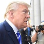 Media Smear on Trump Pardons COLLAPSES Man in suit with photographers in background.
