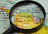 Magnifying glass focusing on Venezuela and Colombia on map.