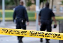 Police officers walking past caution tape at a crime scene