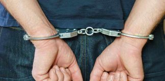 Person in handcuffs behind their back.