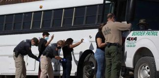 Federal vs. Local: Jail Access Showdown Border patrol officers investigating people near a bus.