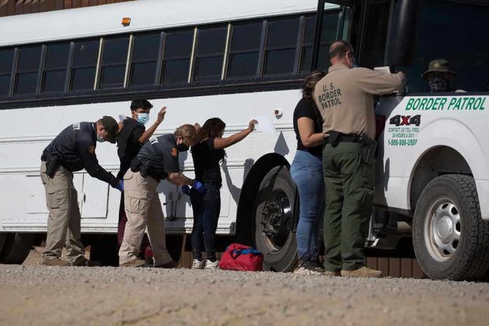 1973414852 Border patrol officers investigating people near a bus.