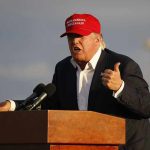 Trump’s Election Army—Will It Intimidate? Person speaking at a podium wearing a red hat.
