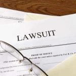 Documents labeled Lawsuit with glasses on top.