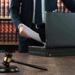Gavel, lawyer, briefcase, and legal books on the table.