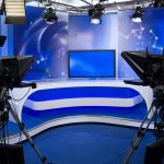 Fake Arcade Scandal: Can We Trust War News? A television studio setup with cameras and a blue backdrop