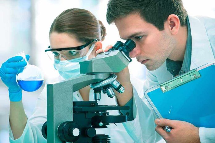 Two scientists conducting an experiment in a laboratory, one looking through a microscope and the other holding a flask with blue liquid