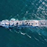 Aerial view of a naval ship navigating through the ocean