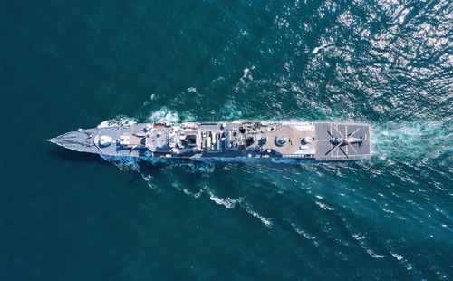 Aerial view of a naval ship navigating through the ocean