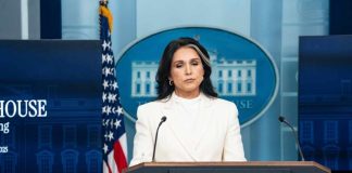 Woman in white suit speaking at White House press podium