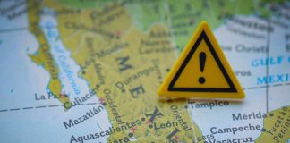 Trump Admin Targets Cartel-Linked Officials, Not Just Street Dealers A close-up of a map of Mexico with a yellow warning sign placed on it