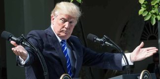 man at podiums with arms outstretched during outdoor press event