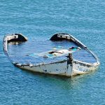 partially sunken boat in calm blue water