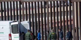 Mystery Crystals Spark Deadly ICE Controversy Border agents escort a group near a tall fence and a patrol van