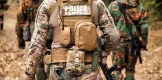 Tactical officers in camouflage gear walking on a forest trail
