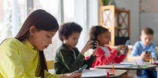 Parents Vs. Policy: Showdown In Schools Children in a classroom focused on their smartphones