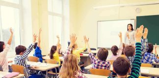 Shock Move Centralizes California Classrooms Students raise hands in a classroom with a teacher at the front