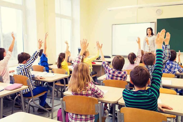 shutterstock_326638589 Students raise hands in a classroom with a teacher at the front