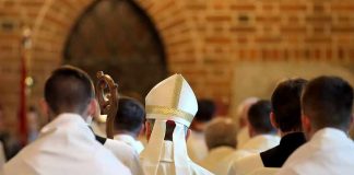 Backroom Deal Frees Pastor—What Got Traded? Bishop in white mitre among clergy during church procession