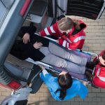 Paramedics load a patient on a stretcher into an ambulance