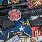 Rifles and pistol with ammunition on American flag