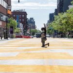 Person kneeling on painted city street raising fist